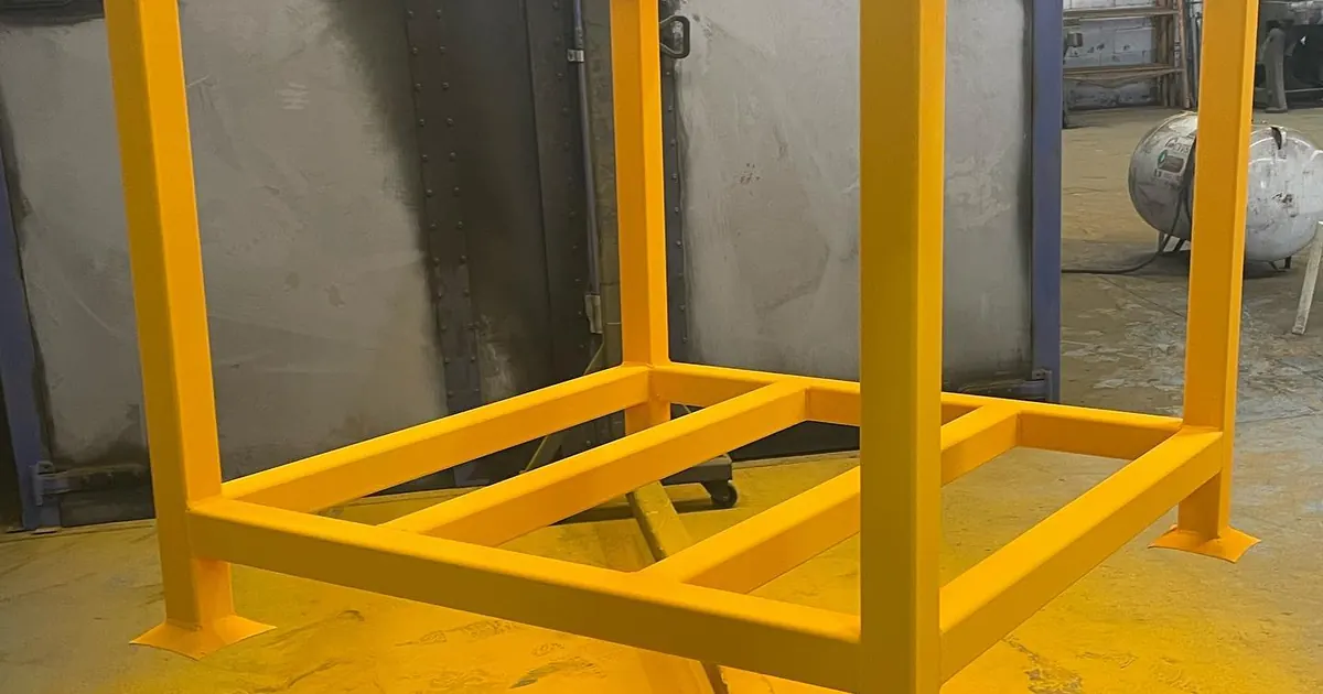 Estructura metálica amarilla con pintura electrostática texturizada colgada en la línea de pintura de Steel Paint