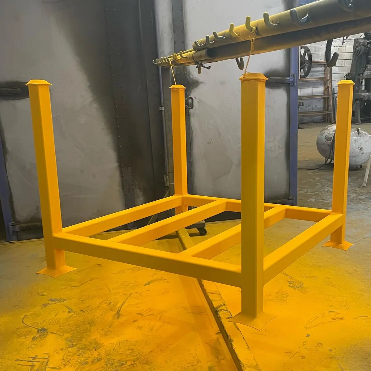 Estructura metálica amarilla con pintura electrostática texturizada colgada en la línea de pintura de Steel Paint